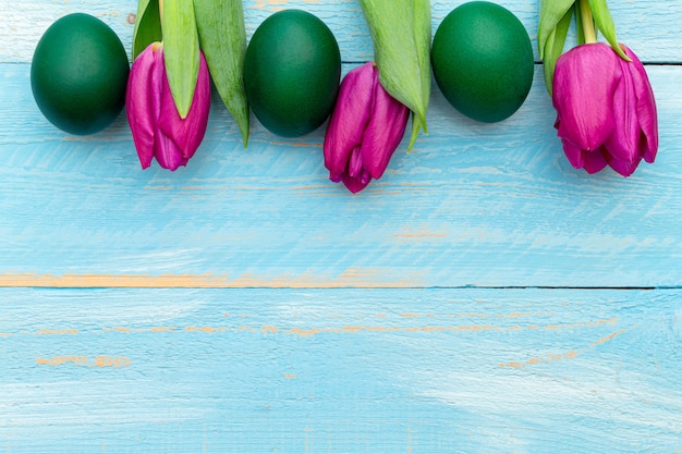 Huevos de Pascua con coloridos tulipanes rosados en una primavera pintada de azul con espacio de copia.