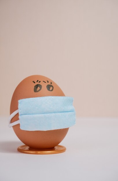 Huevos de Pascua con conceptos de protección antivirus. Huevos de Pascua en una máscara médica para decorar las vacaciones de Semana Santa. Sobre un fondo melocotón con copyspace.