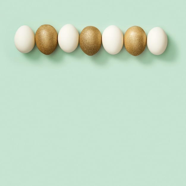 Huevos de Pascua decorados dorados y blancos sobre fondo verde. Tarjeta de Pascua feliz, postal
