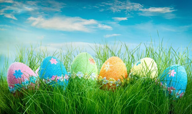 Huevos de pascua decorados en la hierba sobre fondo de cielo azul