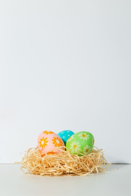 Huevos de Pascua decorados en el nido sobre un fondo blanco.