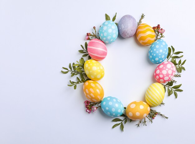 Huevos de Pascua decorativos y flores sobre fondo blanco.