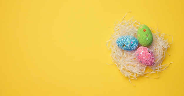 Huevos de pascua decorativos en un nido de papel blanco cortado, vista superior