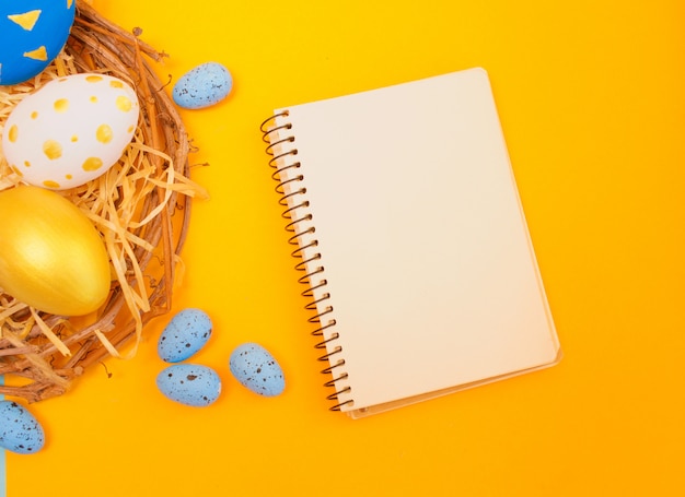 Huevos de Pascua dorados y azules en un nido y cuaderno