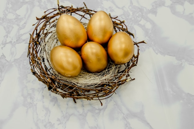 Huevos de Pascua dorados en una caja con estrellas doradas sobre fondo blanco