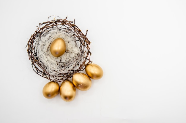 Huevos de Pascua dorados en una caja con estrellas doradas sobre fondo blanco