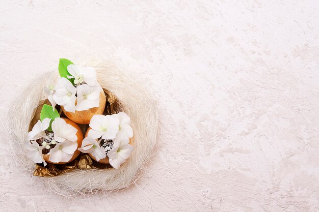 Huevos de Pascua dorados con flores en un nido sobre una superficie con textura