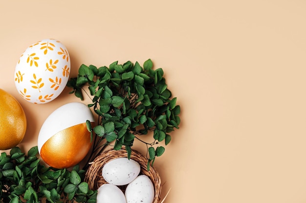 Huevos de Pascua dorados con flores verdes sobre fondo beige Concepto de vacaciones Feliz Pascua cardx9