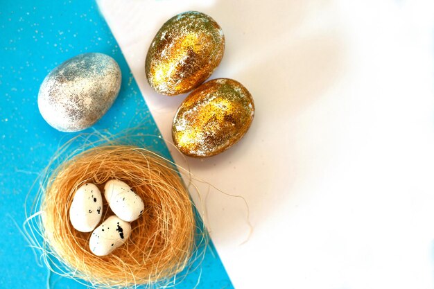 Huevos de Pascua dorados y plateados con nido sobre un fondo azul Concepto de Pascua Feliz Pascua Copiar espacio