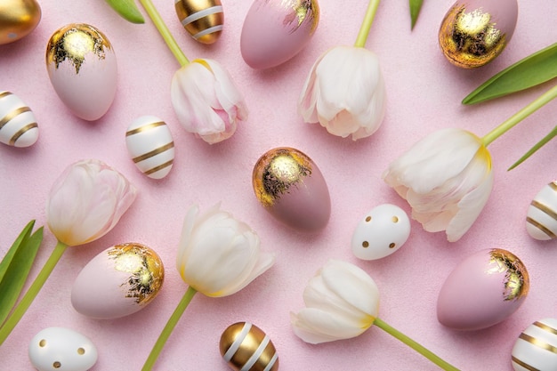 Huevos de Pascua dorados y tulipanes rosas sobre fondo rosa.