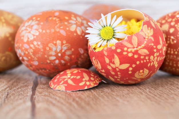 Huevos de Pascua y flor de Margarita en mesa de madera