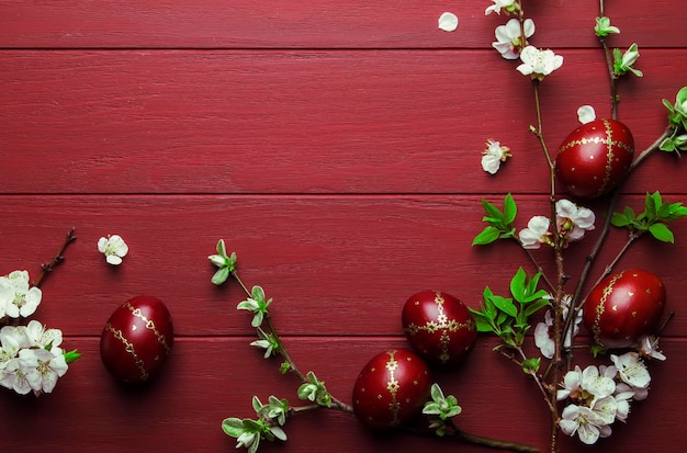 Huevos de Pascua y flores blancas de primavera sobre fondo de madera roja de Pascua con espacio para copiar