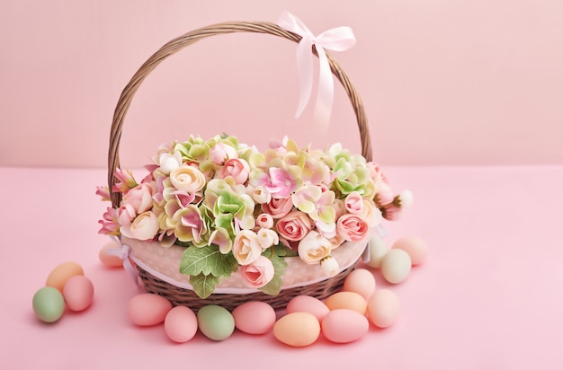 Huevos de Pascua y flores. Canasta de Pascua con flores y huevos sobre fondo rosa