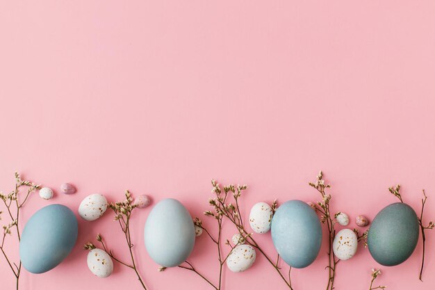 Huevos de pascua y flores planas sobre fondo rosa espacio para texto Tarjeta de felicitación fondo de pascua