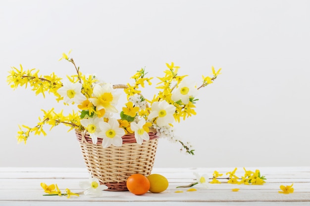 Huevos de Pascua con flores de primavera en la mesa de madera blanca