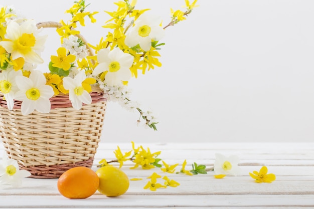 Huevos de Pascua con flores de primavera en la mesa de madera blanca