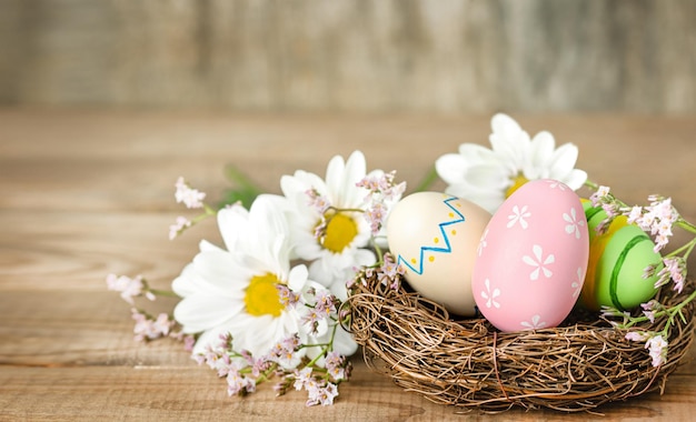 Huevos de pascua y flores de primavera en una mesa de madera