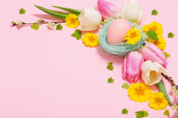 Huevos de Pascua y flores de primavera sobre fondo rosa