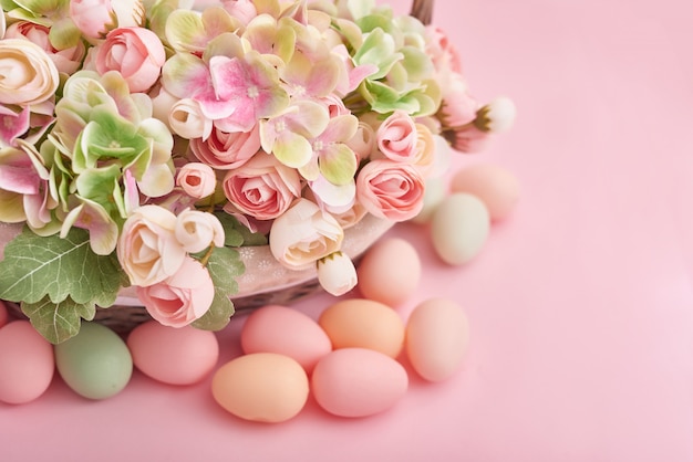 Huevos de Pascua y flores sobre fondo rosa