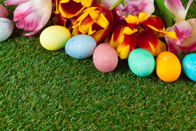 Huevos de Pascua con flores sobre hierba verde