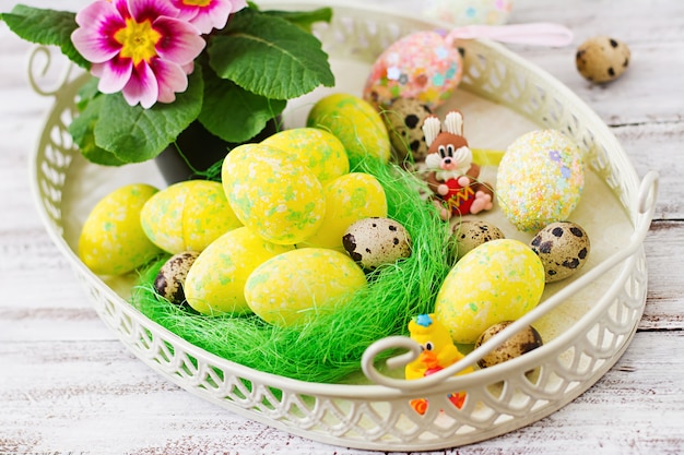 Huevos de Pascua y flores sobre una mesa de madera clara