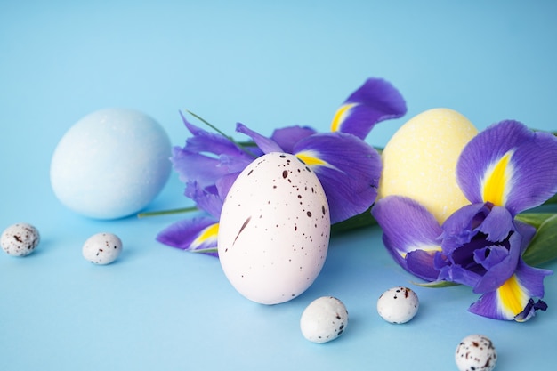 Huevos de Pascua con flores sobre una superficie azul. De cerca.