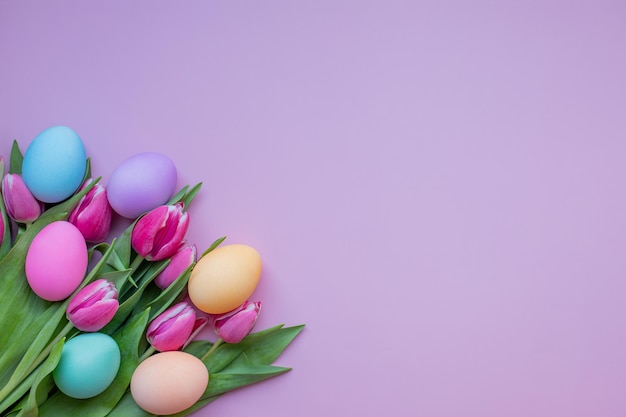Huevos de Pascua y flores de tulipán sobre un fondo rosa Tarjeta de Pascua con huevos decorados y flores de tulipán Huevos de Pascua cristianos sobre un fondo rosa con espacio para copiar texto