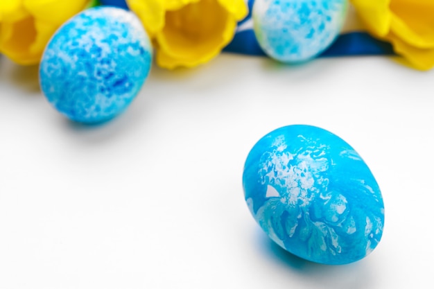 Huevos de Pascua con flores de tulipanes sobre fondo blanco.