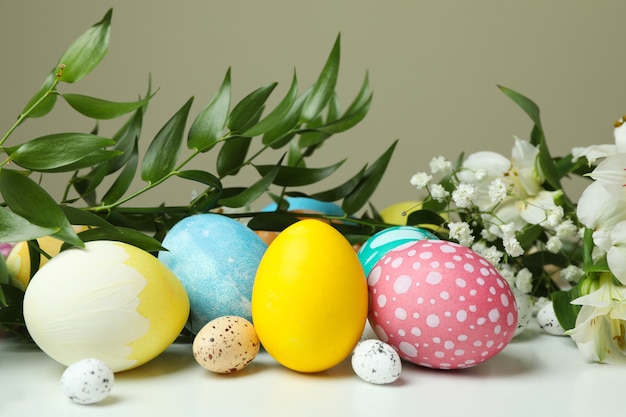 Huevos de Pascua y hermosas flores en mesa blanca