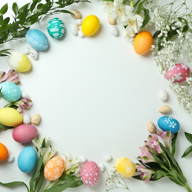 Huevos de Pascua y hermosas flores sobre fondo blanco, espacio para texto