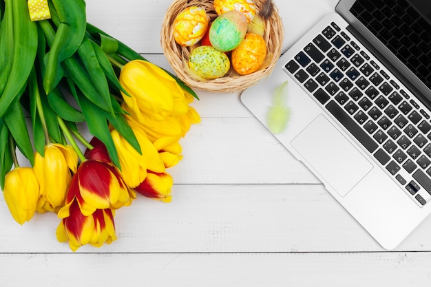 Huevos de pascua, laptop y ramo de tulipanes