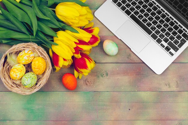 Huevos de pascua, laptop y ramo de tulipanes