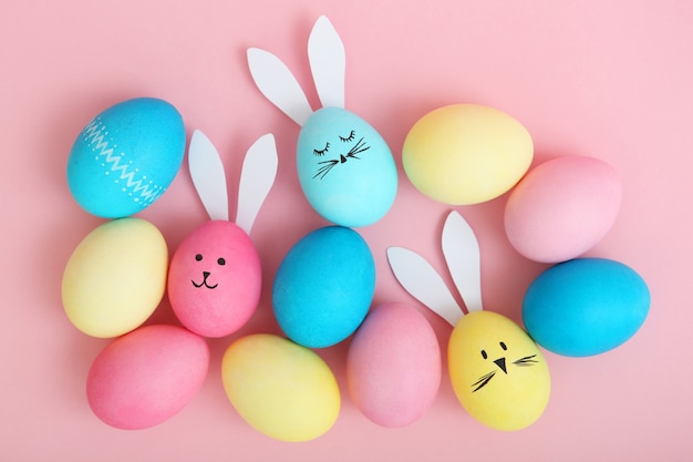 Huevos de Pascua con lindas caras y orejas sobre un fondo de color