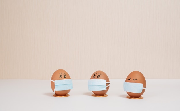huevos de pascua en una máscara médica para decorar las vacaciones de pascua sobre un fondo melocotón con copyspace
