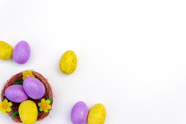 Huevos de Pascua morados y amarillos en un nido sobre un fondo blanco Vista desde arriba Copiar espacio