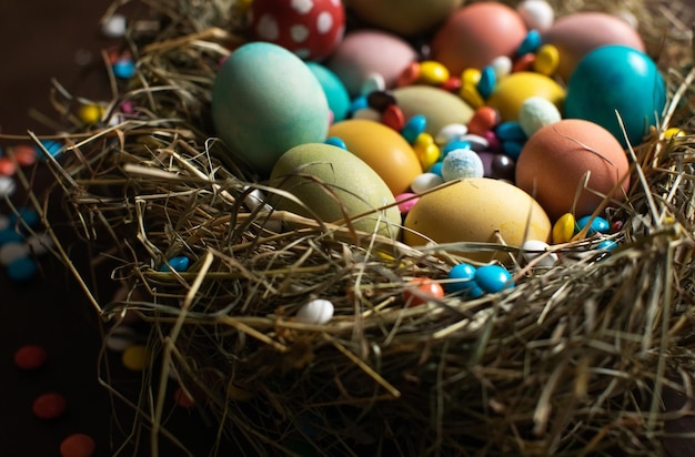Huevos de Pascua multicolores y dulces de chocolate en el nido Felices Pascuas
