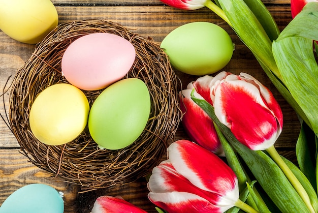 Huevos de Pascua multicolores con flores de tulipanes sobre fondo de madera