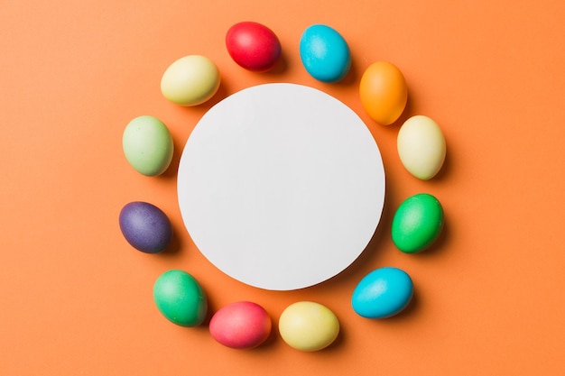 Huevos de Pascua multicolores de marco redondo con papel blanco en blanco sobre un fondo marrón espacio de primer plano para texto en blanco para el diseño imagen tintada de enfoque selectivo