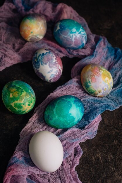 Huevos de Pascua multicolores de tonos azules sobre un fondo de tela multicolor. Huevos de Pascua en clave baja