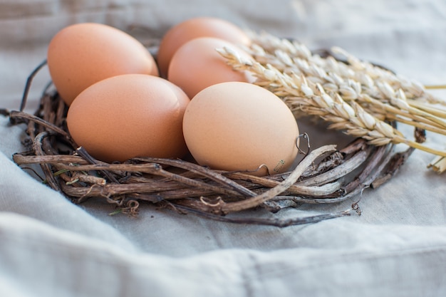 Huevos de Pascua naturales en un nido de mimbre en una servilleta de lino.