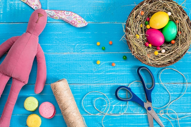 Huevos de pascua en nido y conejo en tablones de madera rústicos azules