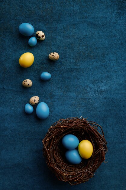 Huevos de Pascua en nido decorativo sobre fondo de tela azul