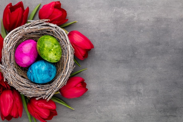 Huevos de Pascua en el nido. Flores de primavera tulipanes. Tarjeta de felicitación de primavera.