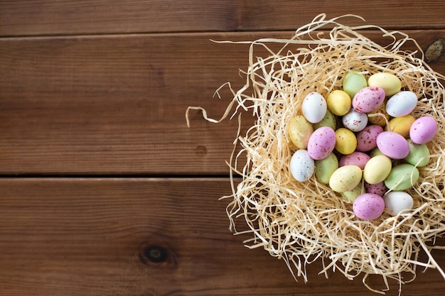 huevos de Pascua en nido de paja en una mesa de madera