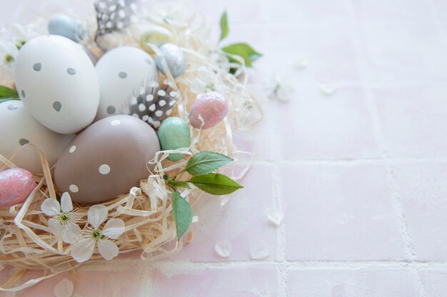 Huevos de pascua en nido de paja sobre un fondo de mosaico rosa