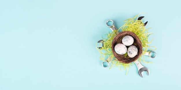 Huevos de Pascua en un nido de pájaros, llaves y hierba verde, tarjeta de felicitación navideña con herramientas de reparación, primavera