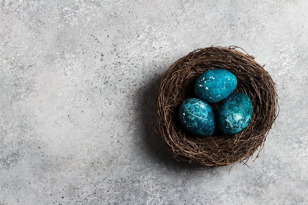 Huevos de pascua en nido pintados a mano en color azul sobre fondo claro