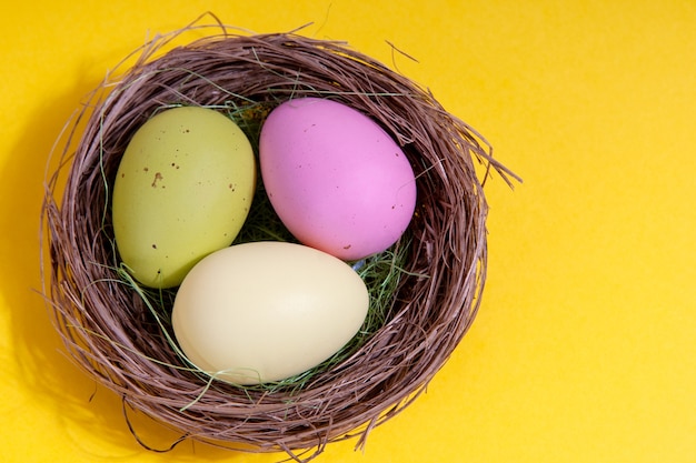 Huevos de Pascua en un nido sobre un fondo amarillo. Concepto de pascua