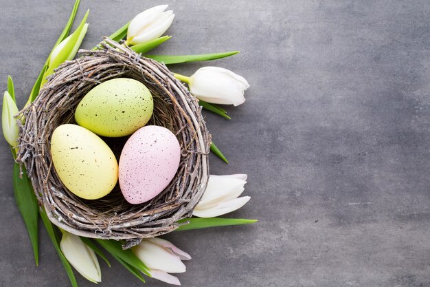 Huevos de Pascua en el nido sobre un fondo gris. Tarjeta de felicitación de primavera.