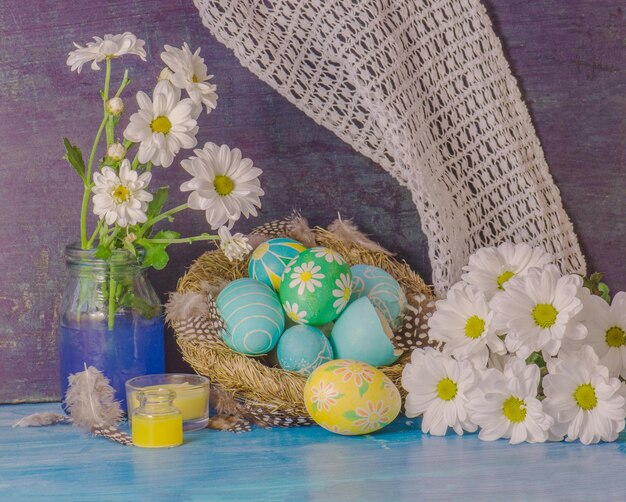 Huevos de Pascua en el nido sobre fondo de madera rústica Huevos de Pascua y margaritas en tablones de madera